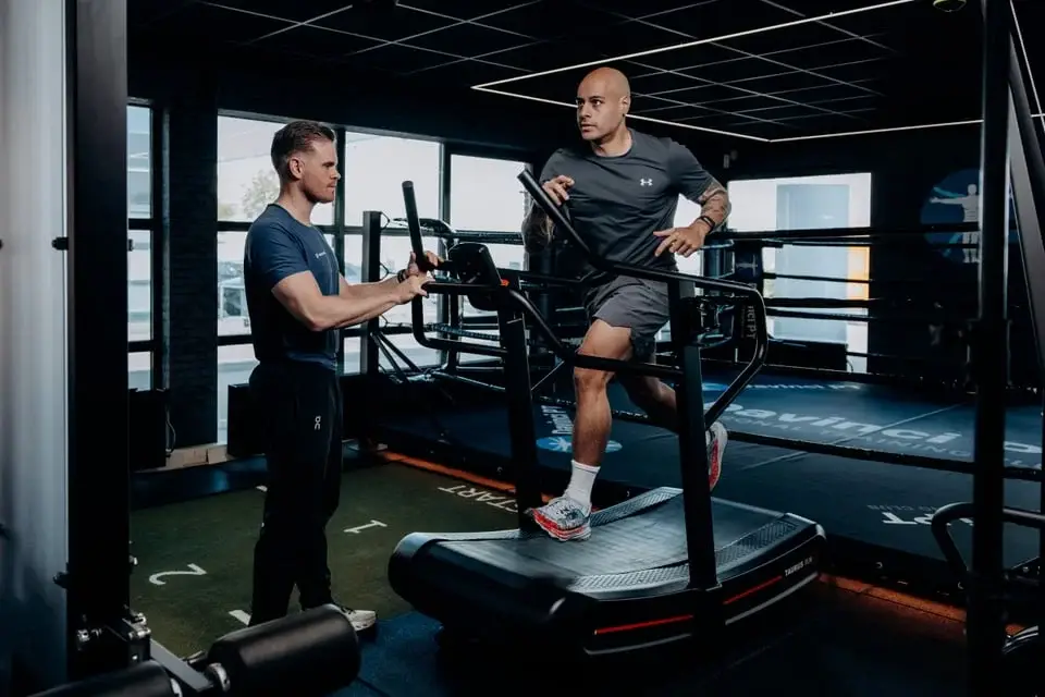Sporter op de loopband met coach in de gym in Barendrecht